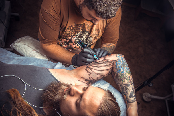 Tattooer κάνει τατουάζ στην αίθουσα δερματοστιξιών - Φωτογραφία, εικόνα