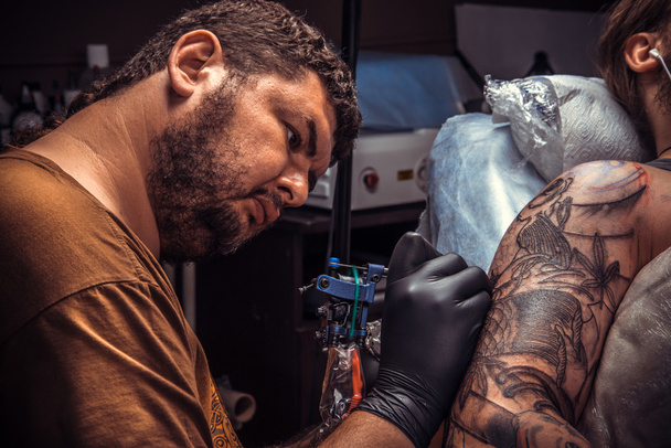 Tattooer posing in tattoo parlour - Foto, afbeelding