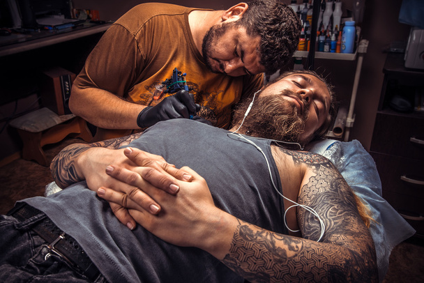 Tatoueur faisant le tatouage dans le salon de tatouage
 - Photo, image