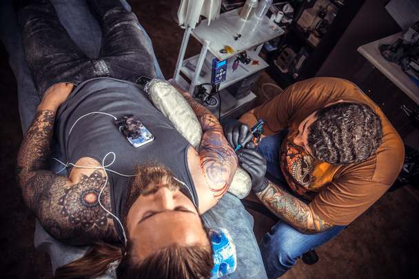 Artista profesional del tatuaje trabajando tatuajes en salón de tatuajes
 - Foto, Imagen