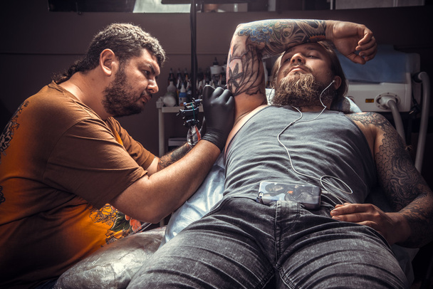 Татуировщик делает татуировки в тату-салоне
 - Фото, изображение