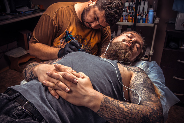 Człowiek sobie rękawice robocze tatuażu w salonie tatoo - Zdjęcie, obraz