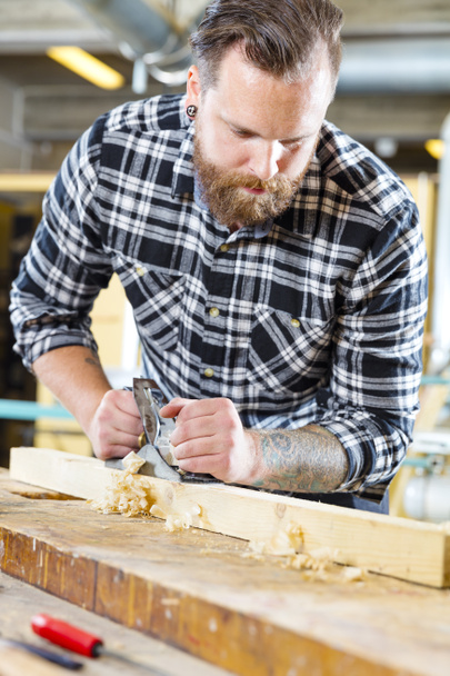 Trabajos de carpintería con cepilladora sobre tabla de madera en taller
 - Foto, imagen