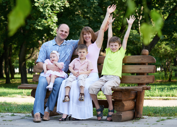 šťastný rodinný portrét na venkovní, skupinu pěti lidí sedí na dřevěné lavici v městském parku, letní sezóny, dítě a rodič - Fotografie, Obrázek