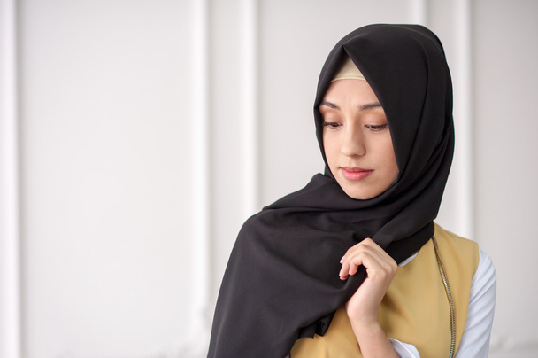 studio muotokuva kaunis nuori nainen Lähi-idän ulkonäkö moderni musliminaisten vaatteet ja huivi hänen päänsä, kevyellä taustalla klassinen
 - Valokuva, kuva