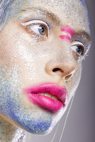 女性の顔に創造的なメイクアップ。ピンクの唇。彼の上の青いペンキ - 写真・画像