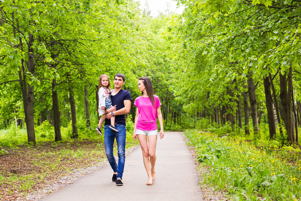 Father, daughter and mother walking outdoors. Happy family. - Photo, Image