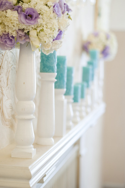 Disposizione floreale con fiori bianchi e blu e candele su portacandele
 - Foto, immagini