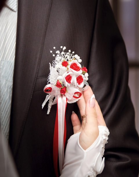 Mariée portant des fleurs boutonnière sur marié en costume noir
 - Photo, image