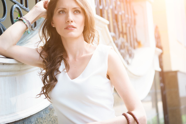 Pensive young brunette in white dress outdoors - 写真・画像