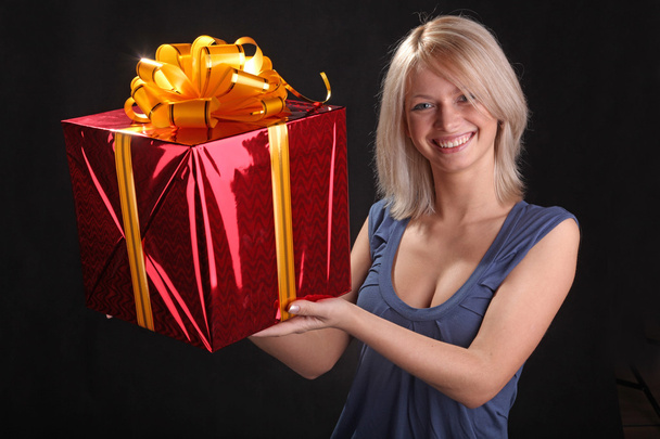 girl gives a gift to the outstretched hands of on black background - Photo, Image
