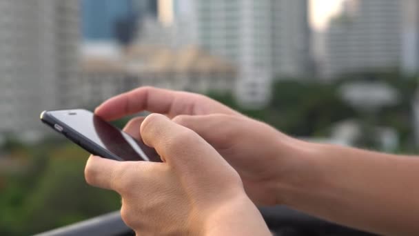 Man surfen op sociale Net gebruik van mobiele telefoon op moment van de avond op dak in grote stad. Close-Up. 4k - Video