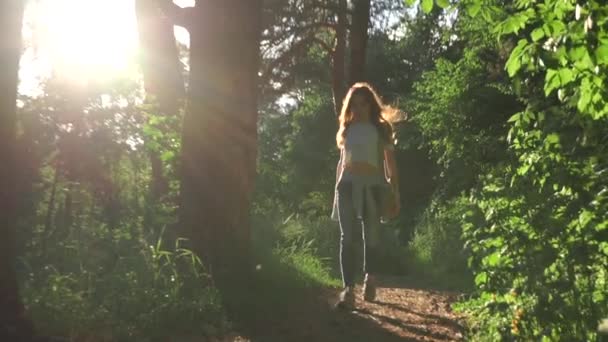 Brunette girl walking towards camera in sunset coniferous forest. Zoom out slow motion shot - Video