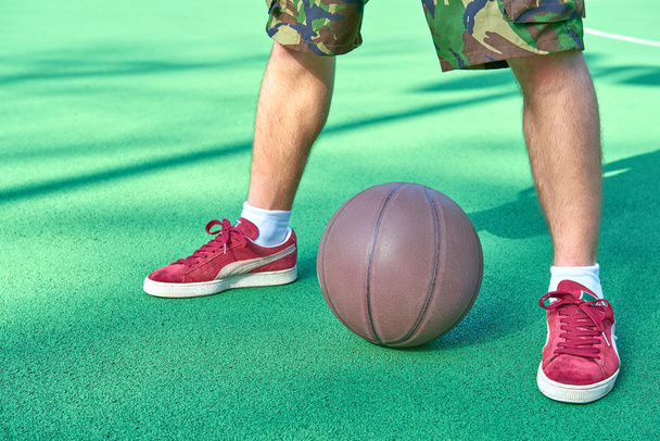 Πόδια στέκεται κοντά σε μπάλα μπάσκετ - Φωτογραφία, εικόνα