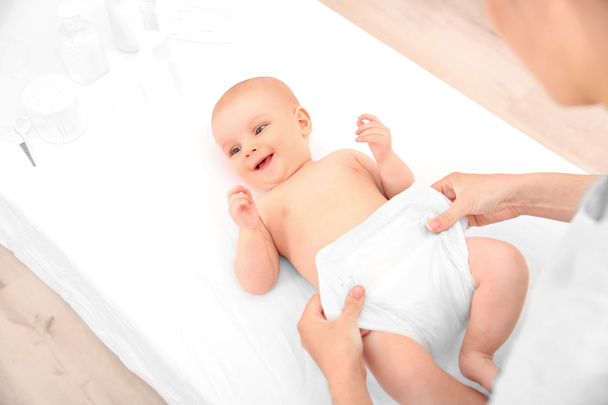 Mother changing diaper to little baby on table - Foto, Bild