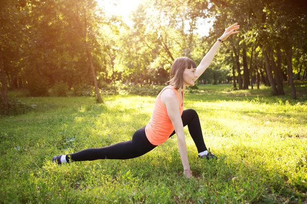 Young woman stretching in a park - Fotoğraf, Görsel