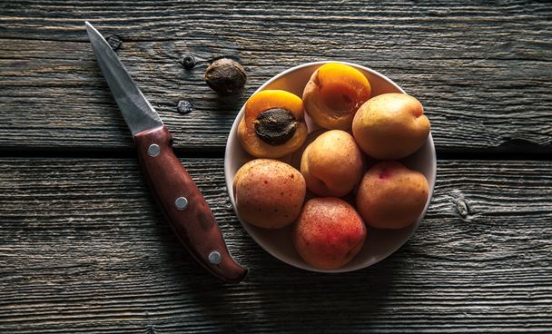 Delicious fruit. Apricots with a knife on a wooden background. Country style. Food - Фото, зображення