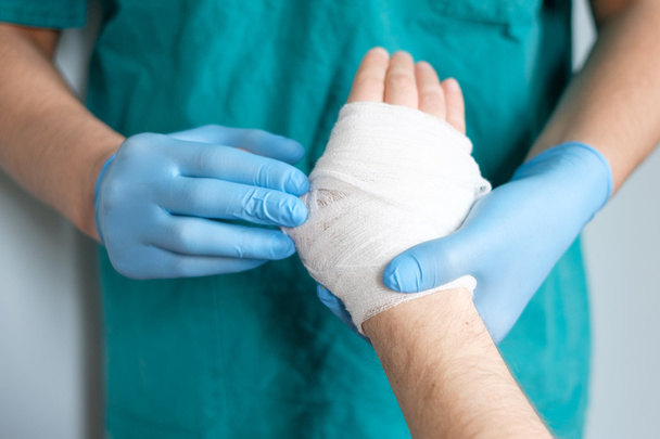 close up of doctor bandaging one hand after an accident - Photo, image