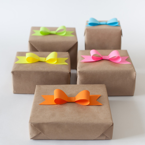 Gifts wrapped in kraft paper. Coloured bright paper bows. - Фото, зображення