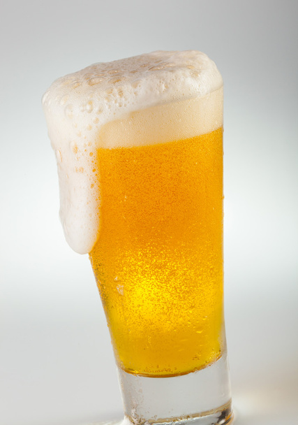 Vaso de cerveza desbordante con la cabeza espumosa
 - Foto, imagen