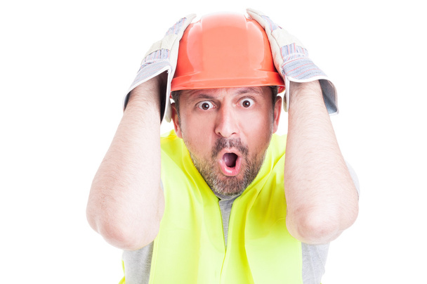 Shocked young builder holding his head looking desperate - Фото, зображення