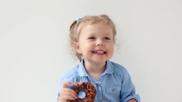Little girl biting a chocolate donut - Footage, Video