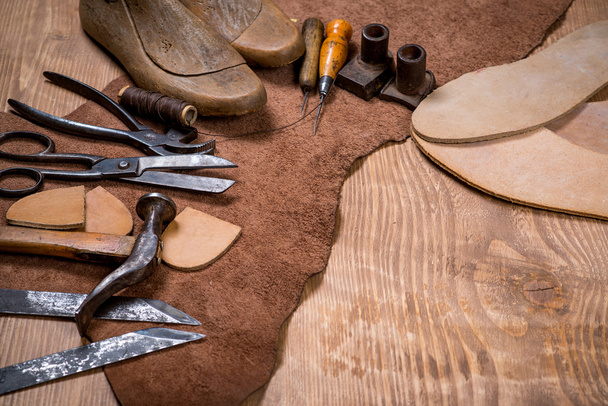 Set lederen craft tools op houten achtergrond. Werkplaats voor schoenmaker. - Foto, afbeelding