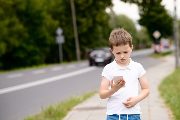 child playing mobile games on smartphone on the street - Foto, afbeelding
