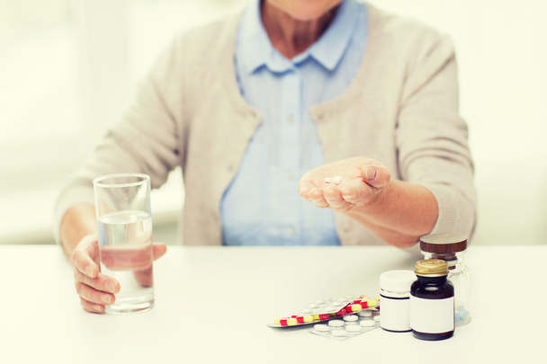 close up of senior woman with water and pills - Фото, изображение