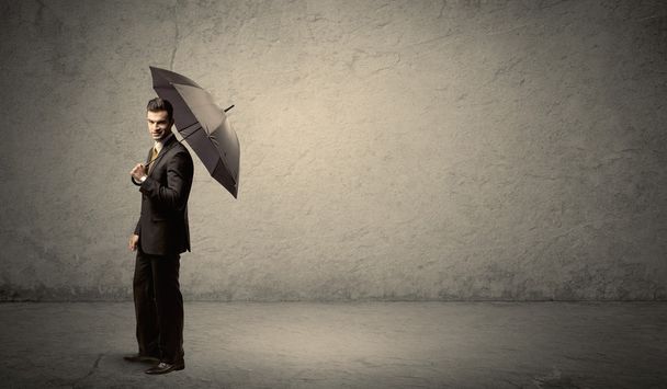 Handsome business man holding umbrella with copy space backgroun - Foto, imagen