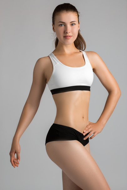 The body sports an attractive woman on a gray background - Foto, afbeelding