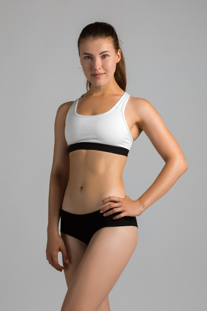 The body sports an attractive woman on a gray background - Foto, Imagen