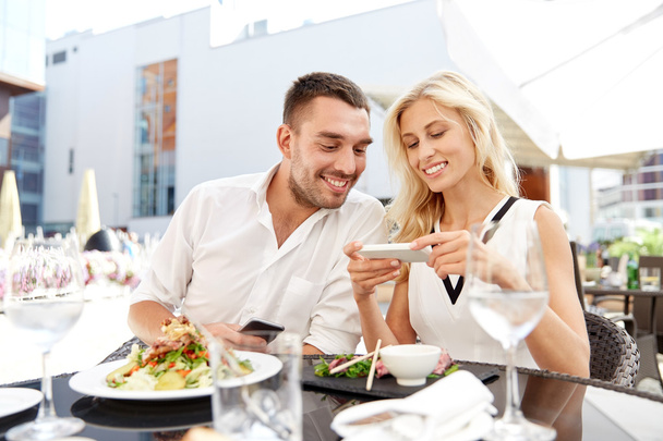 happy couple with smatphone at restaurant terrace - Foto, Imagen