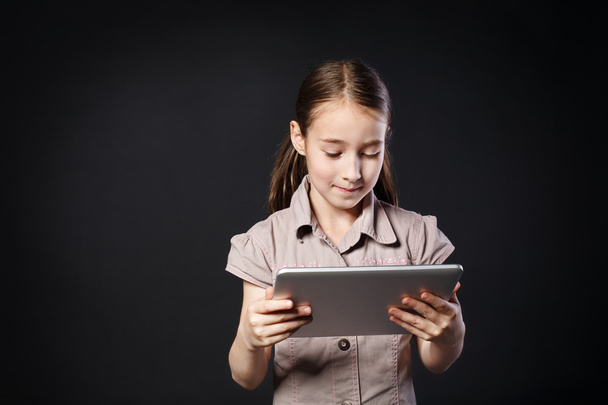Little girl with Digital Tablet at black background - Foto, Bild