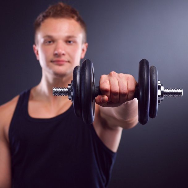 Handsome muscular man working out with dumbbells - Photo, image