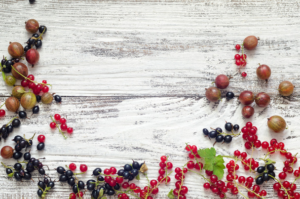 black and red currants gooseberries on white wooden background - Photo, image