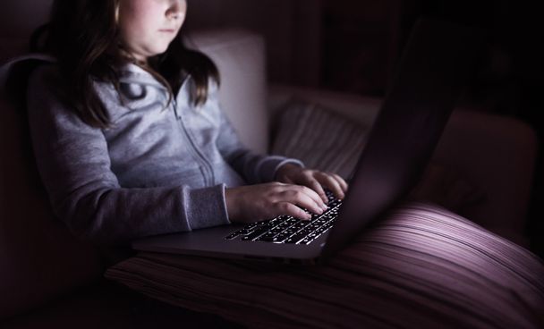 Unrecognizable girl, sitting in a dark, playing with laptop - Valokuva, kuva