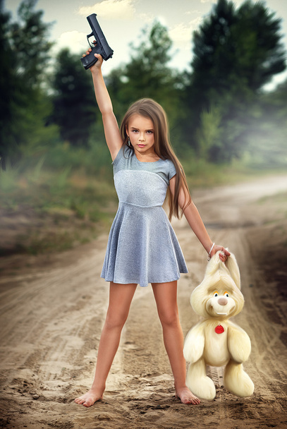 Gedurfd meisje houdt een pistool en pluche konijn - Foto, afbeelding