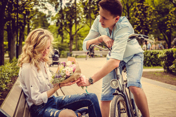 Чоловік на велосипеді дарує квіти своїй дівчині
 - Фото, зображення