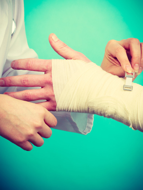 Doctor bandaging sprained wrist - Foto, Imagen