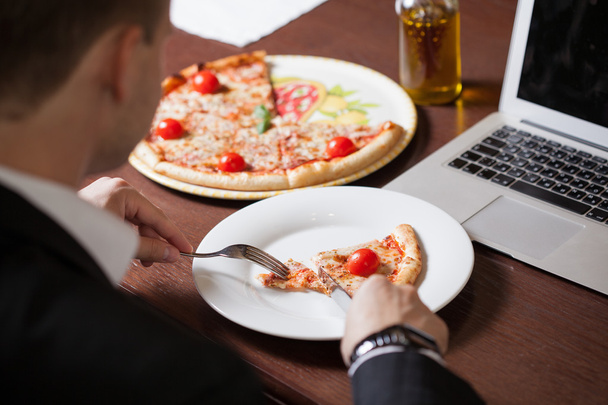 Ο άνθρωπος στο σπίτι τρώει ένα κομμάτι πίτσα και την κοινωνική δικτύωση, με μια - Φωτογραφία, εικόνα