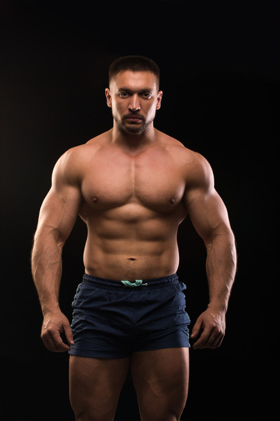 handsome muscular bodybuilder posing on a black background - Фото, зображення
