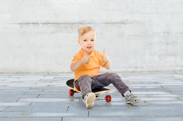 happy little boy on skateboard showing thumbs up - Foto, Imagen