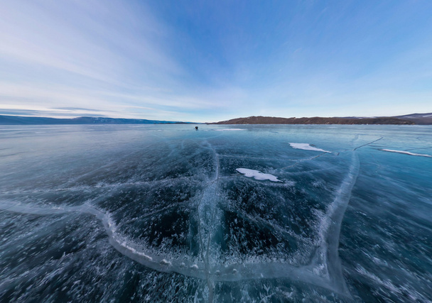 Blue ice of Lake Baikal covered with cracks, cloudy weather at s - Foto, afbeelding
