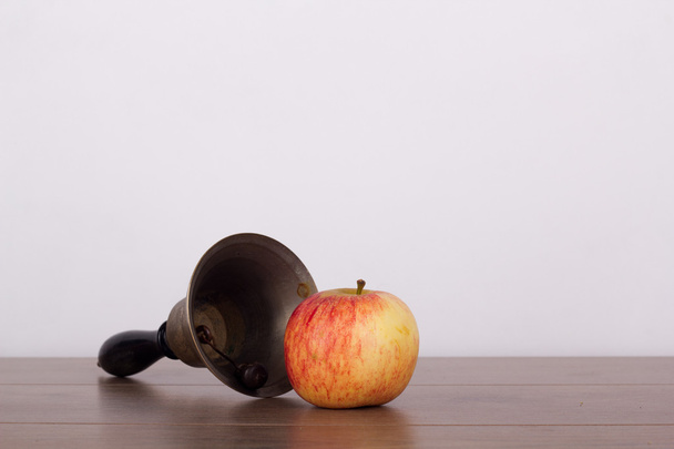 Ντεμοντέ bell και το μήλο σε ξύλινη επιφάνεια - Φωτογραφία, εικόνα