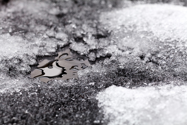 Az olvadó hó aprócska pocsolyája aszfalton - Fotó, kép
