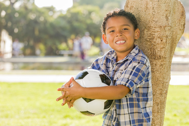Μικτή φυλή αγόρι, κρατώντας την μπάλα ποδοσφαίρου στο πάρκο - Φωτογραφία, εικόνα