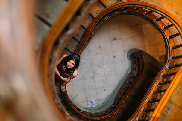 Beautiful brunette model girl posing on winding spiral staircase in an old Lviv house. Top view - Foto, Imagem