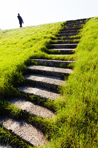 Kamienne schody prowadzące na zielone wzgórze, człowiek przechodzący na szczycie - Zdjęcie, obraz