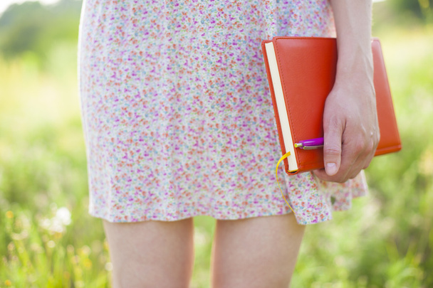 Κορίτσι στο καλοκαιρινό φόρεμα που κρατά ένα βιβλίο. - Φωτογραφία, εικόνα